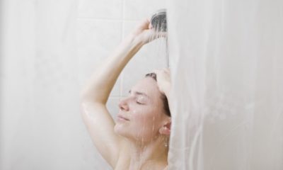 Женщина в душе за шторками в ванной