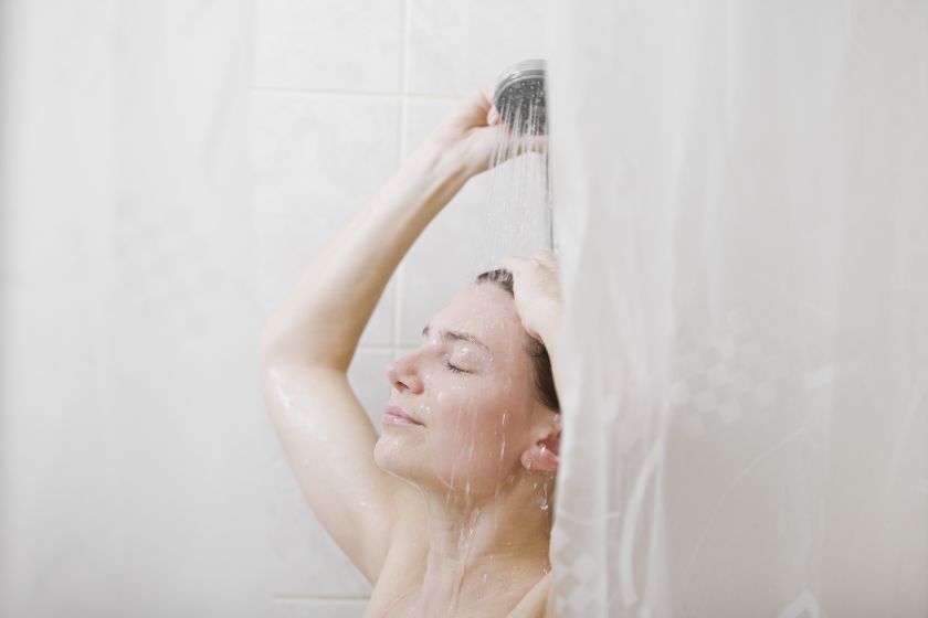 Женщина в душе за шторками в ванной