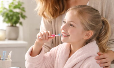 Ребенок чистит зубы в ванной комнате под присмотром взрослого