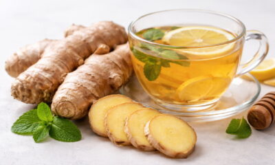 Свежий корень имбиря и нарезанные ломтики рядом с чашкой имбирного чая