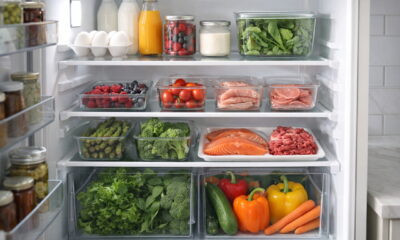 Открытый холодильник с аккуратно разложенными продуктами по полкам, овощи в ящиках, мясо и рыба на нижней полке