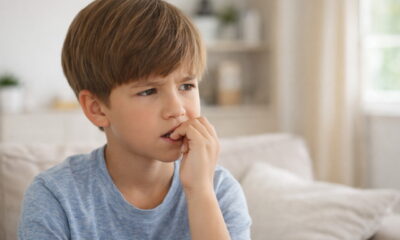 Ребёнок школьного возраста задумчиво грызёт ноготь